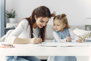 A mother and daughter enjoy a bonding moment while doing homework together indoors.