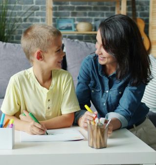 A mother and son happily drawing together in a cozy living room setting, fostering creativity.